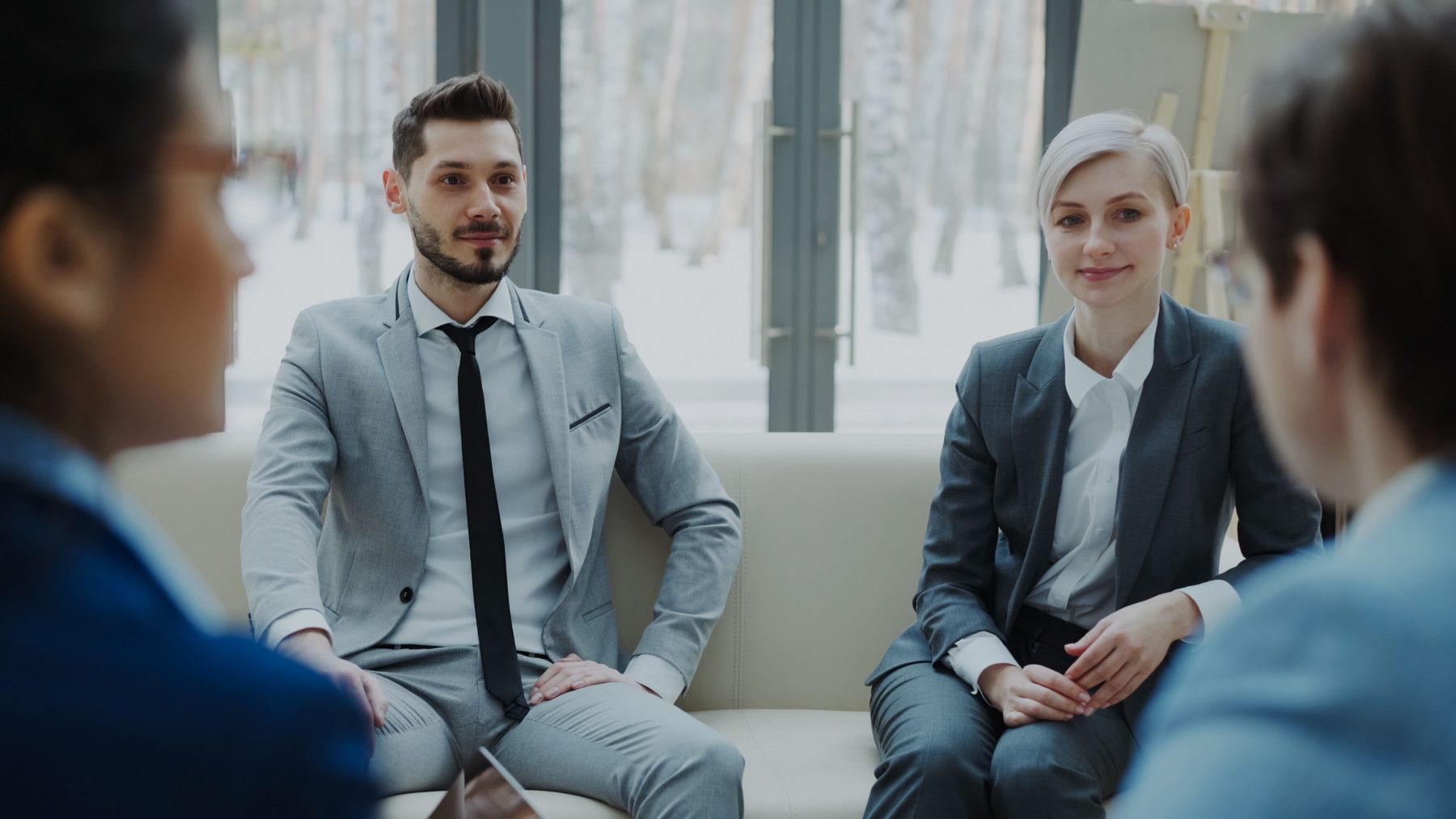 An adviser and a client sitting together on a sofa, relaxed and listening