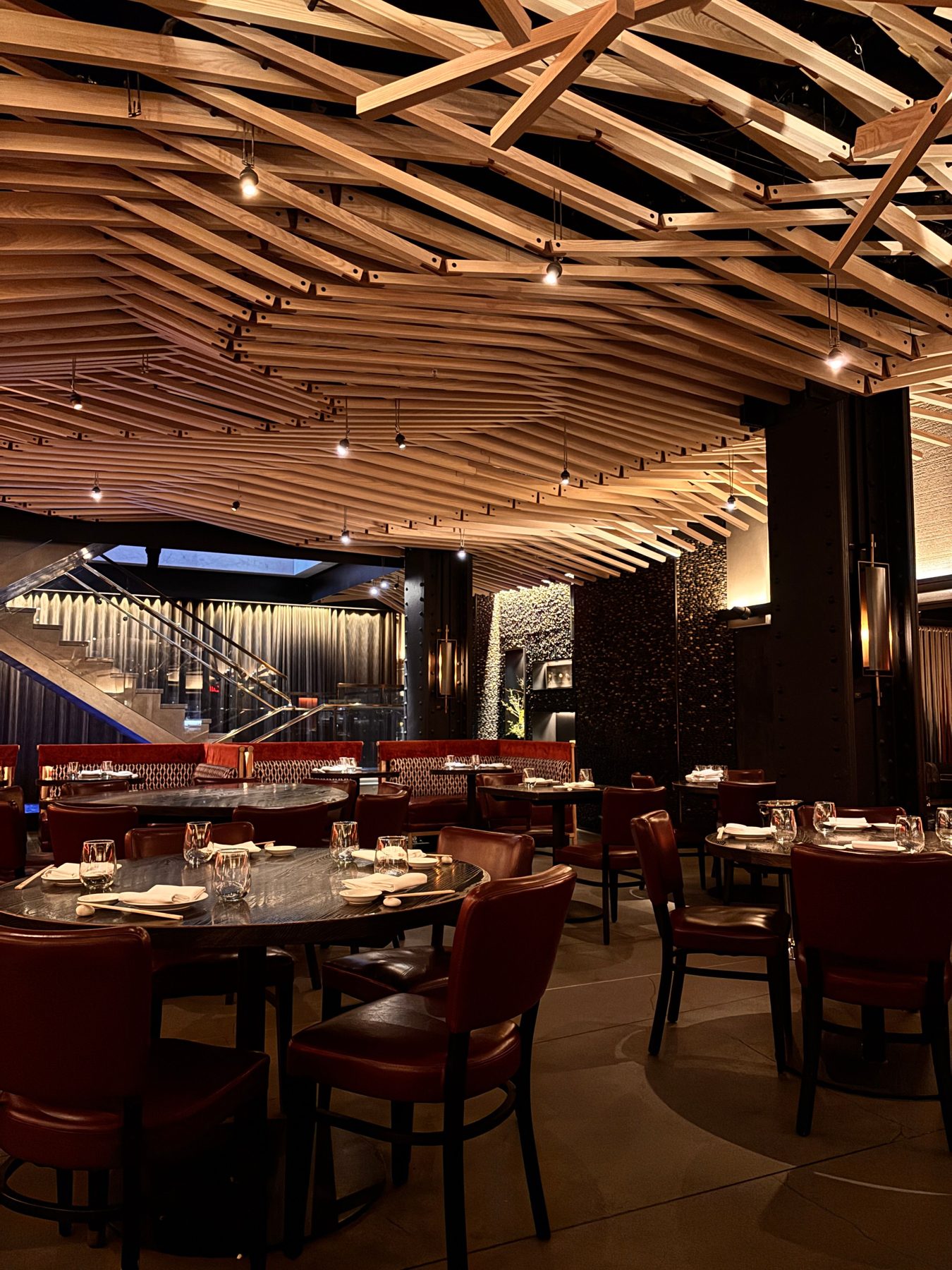A warm, softly lit room with timber ceiling and red leather seats