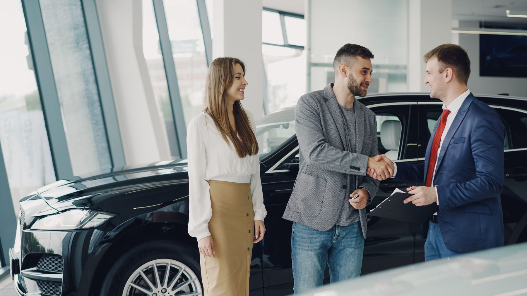 A handshake beside a black car in the showroom