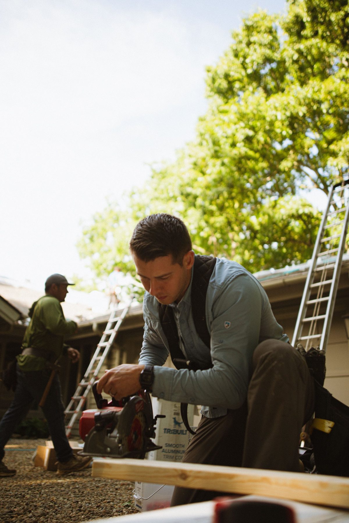 A joiner kneeling beside a ladder on site