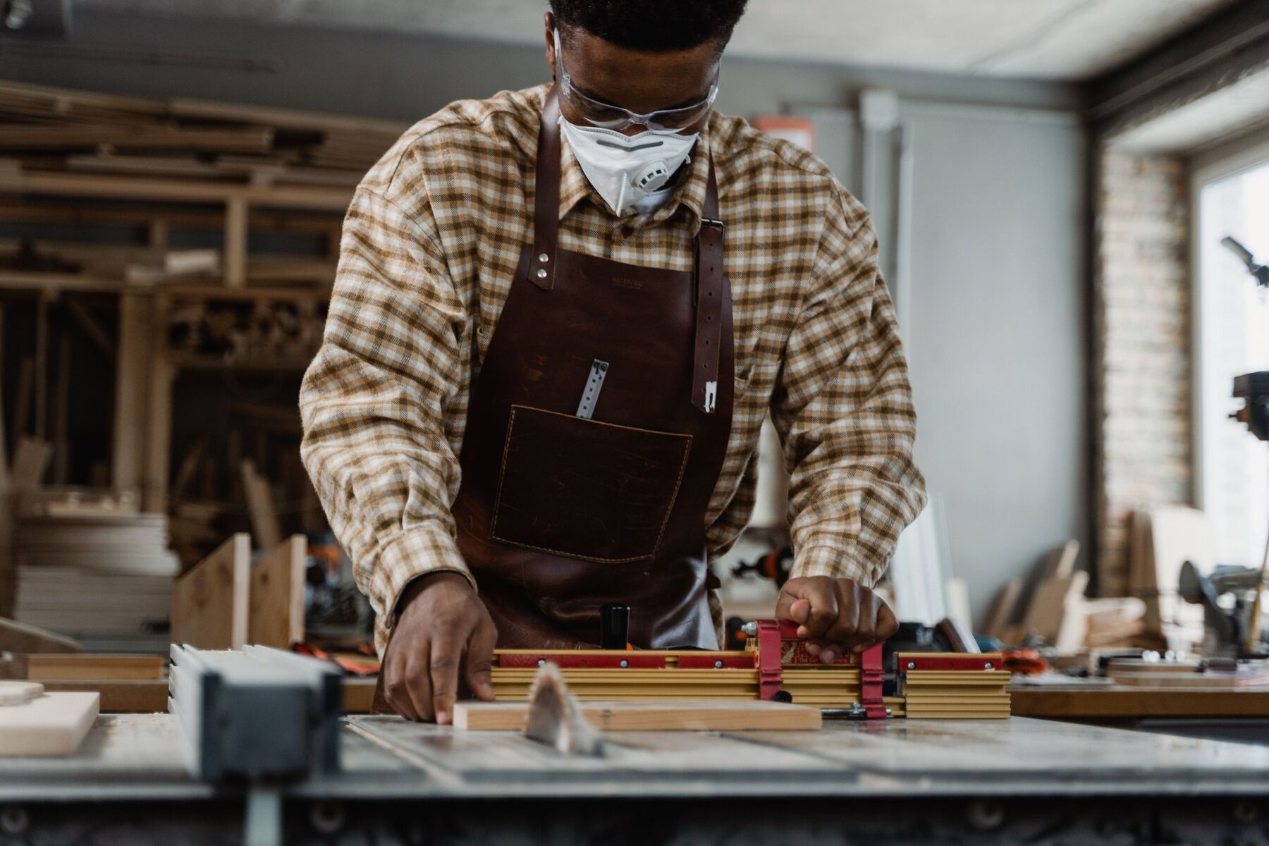A joiner guiding a board through the saw bench in a timber workshop