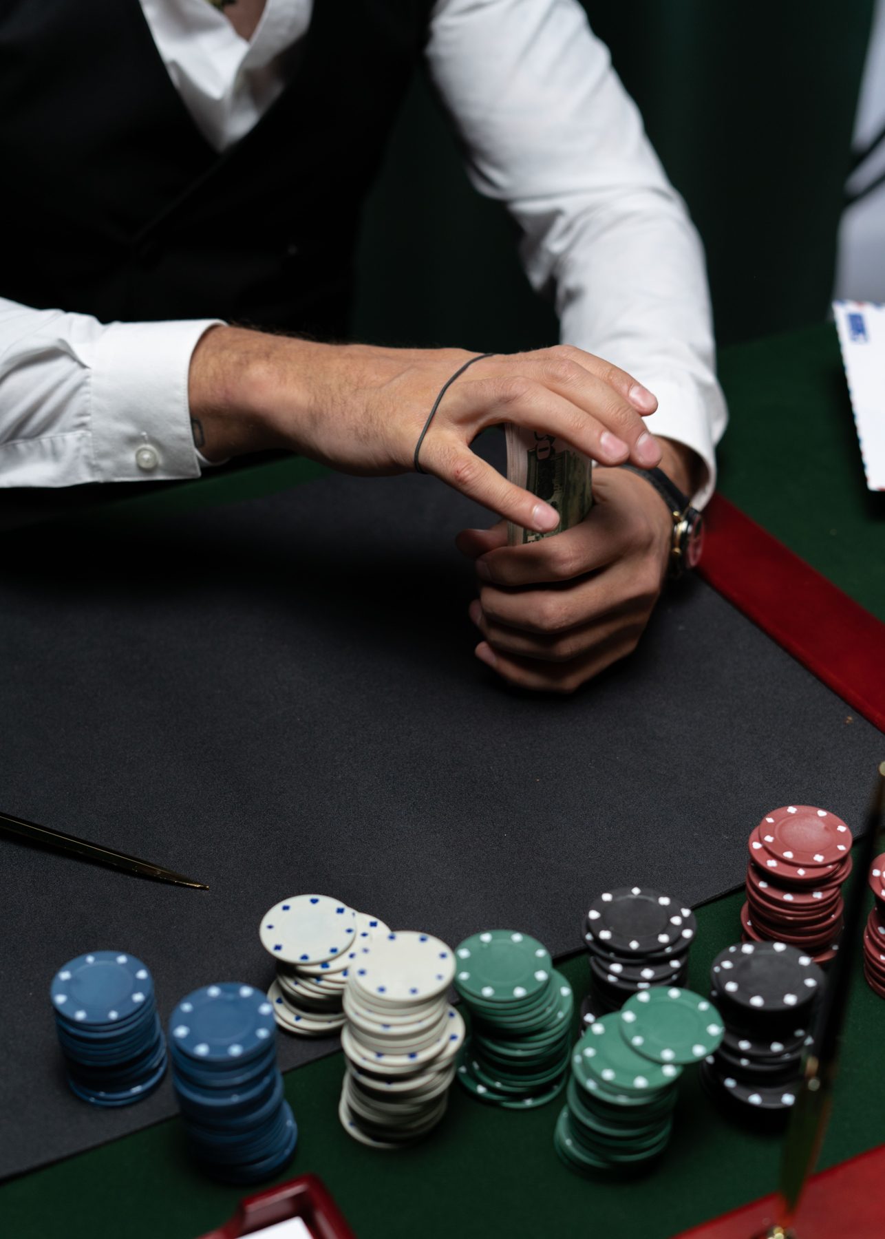 A dealer in a waistcoat holding a deck of cards beside coloured chips