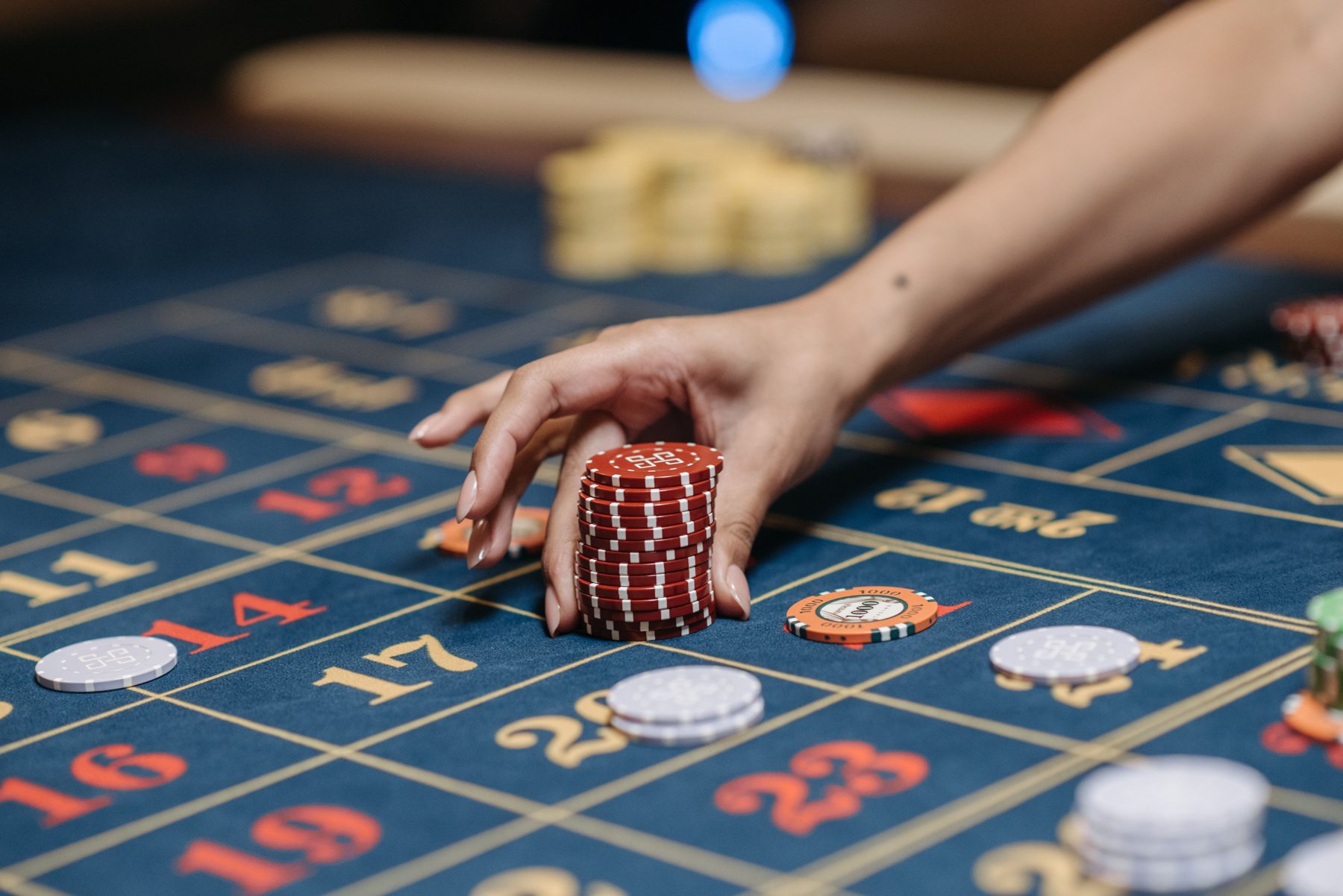 A hand placing red chips on a roulette table