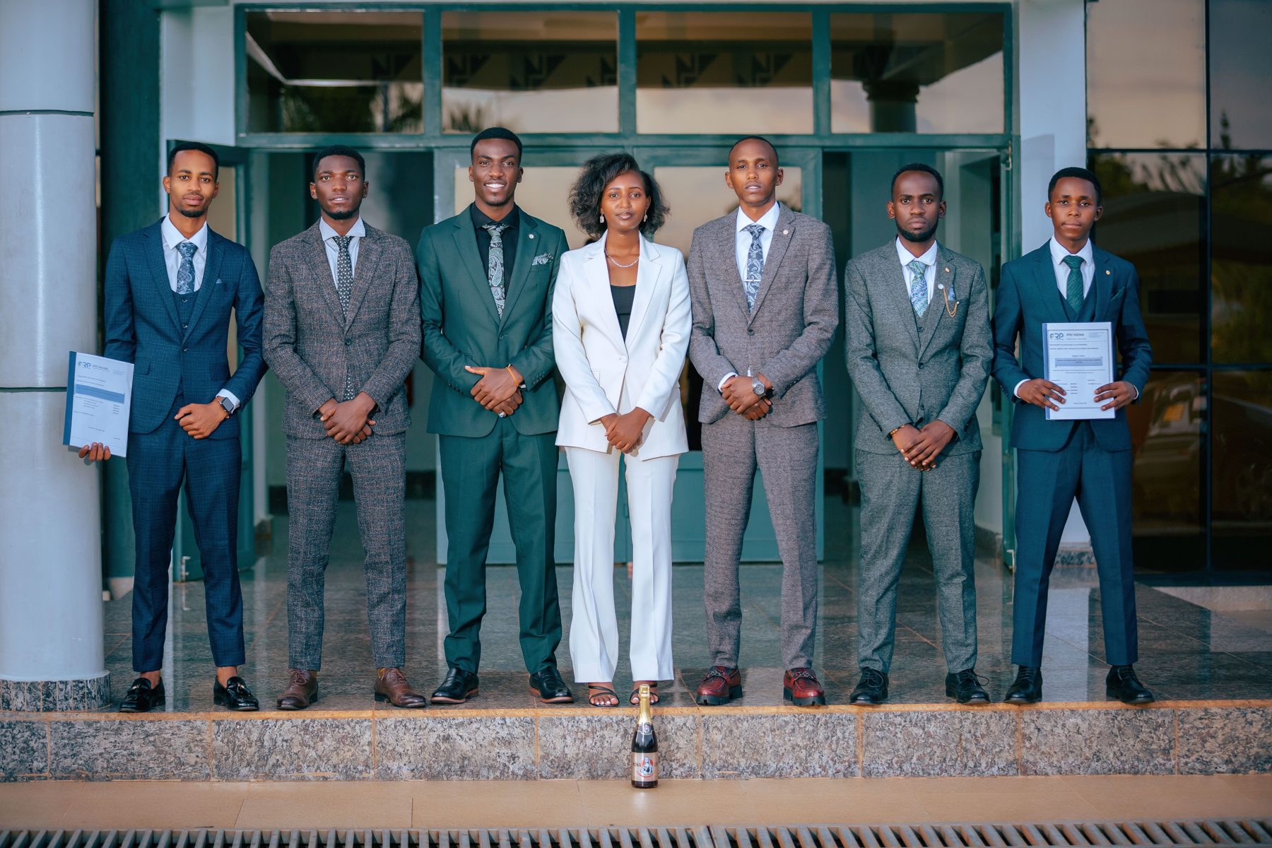 Seven members of the Tallis Brook team in suits standing in a row outside the office